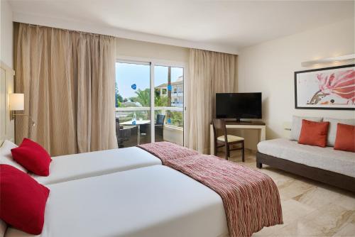 Pokój hotelowy z dużym łóżkiem i kanapą w obiekcie Grupotel Alcudia Suite w Playa de Muro