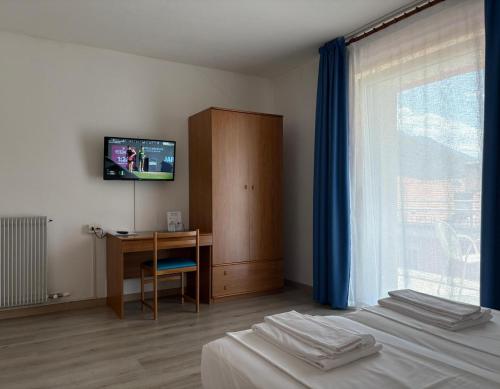 a bedroom with two beds and a desk and a television at Hotel Villa Al Vento in Nago-Torbole