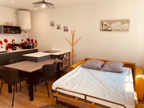 a bedroom with a bed and a table and a kitchen at Le Nid des Charmettes in Saint-Josse