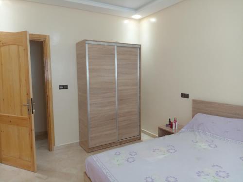 1 dormitorio con cama y armario de madera en كراء يومي, en Aourir