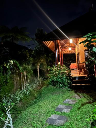 a garden at night with a table and chairs at Rumah Tenun in Karangasem