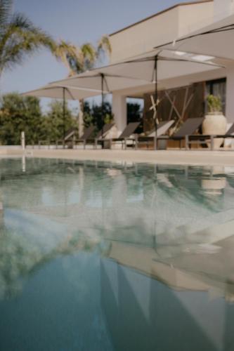 a large swimming pool with chairs and umbrellas at Palmar Boutique Hotel in Campofelice di Roccella