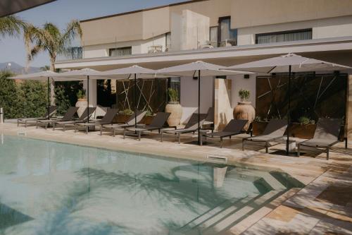 a group of chairs and umbrellas next to a swimming pool at Palmar Boutique Hotel in Campofelice di Roccella