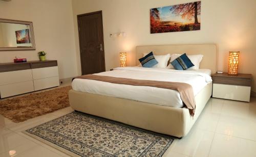 a bedroom with a large bed with two lamps and a rug at Royal Suites Muscat in Ma‘ābīlah