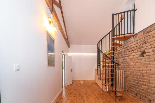 a hallway with a brick wall and a staircase at Gîte des Roussèles - Climatisation, Spa, jardin in Gaillac