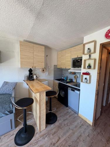 - une petite cuisine avec une table et deux tabourets de bar dans l'établissement Appartement cosy à la montagne aux pieds des pistes pour 4 personnes et 1 bébé, à Taninges