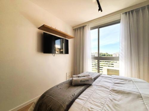 a bedroom with a bed and a large window at UniHome Niterói in Niterói