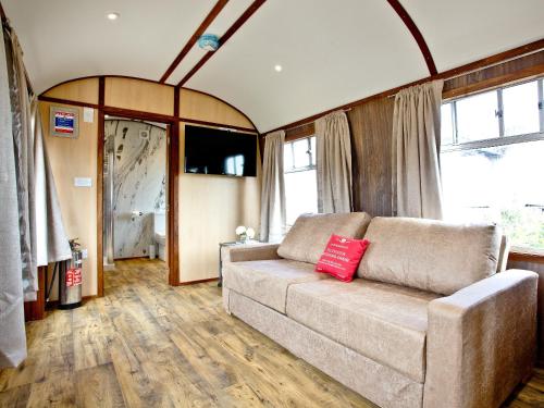 a living room with a couch with a red pillow at Brunel Boutique Railway Carriage 4 in Dawlish Warren