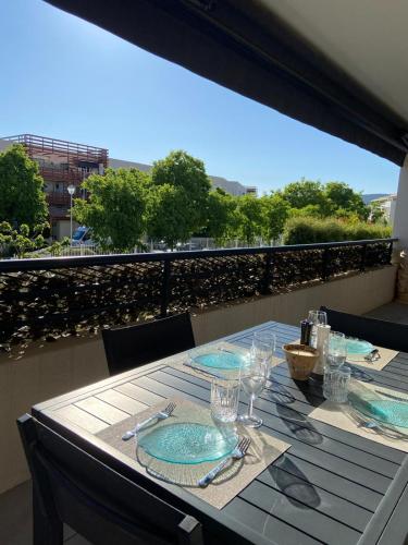 una mesa con platos y vasos en el balcón en La Huperie, en Saint-Cyr-sur-Mer