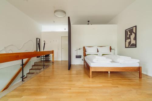 a white bedroom with a bed and a staircase at MARAL Loft München Bogenhausen in Munich
