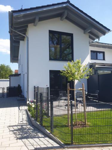 a white house with a fence and a tree at Appartement an der alten Linde in Weil
