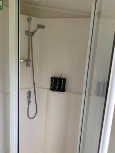 a shower with a shower head in a bathroom at Beautiful beach themed static caravan in Hastings
