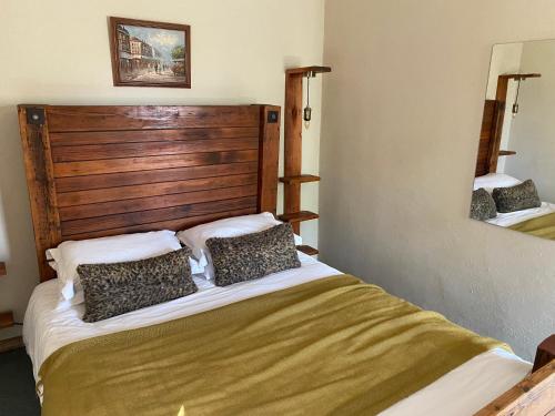 a bedroom with a large bed with a wooden headboard at Soetvlei Farm Cottage in Rustenburg