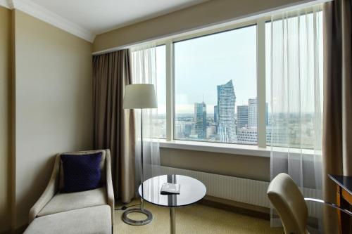a hotel room with a chair and a table and a window at Warsaw Presidential Hotel in Warsaw