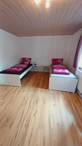 two beds in a room with wooden floors at Einfache 2 Zimmer Wohnung mit Parkplatz nur 8 Min nach Bayreuth in Mistelgau