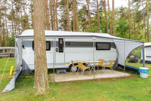 a white caravan with a tent and a table and chairs at Urlaub im Wohnwagen mitten im Wald in Lütow