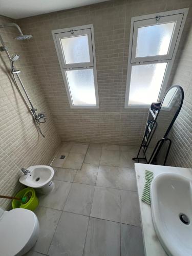 a bathroom with a sink and a toilet and two windows at Joli et confortable appartement in Cabo Negro