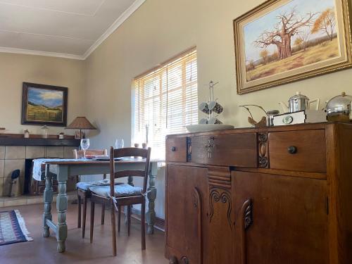 una sala da pranzo con tavolo e comò in legno di Soetvlei Farm Cottage a Rustenburg