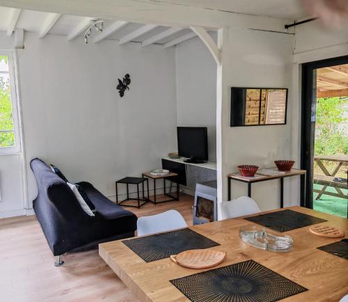 ein Wohnzimmer mit Tisch und Couch in der Unterkunft Gîte Nature sur LAC avec accès PISCINE et PONTON in Éguzon-Chantôme