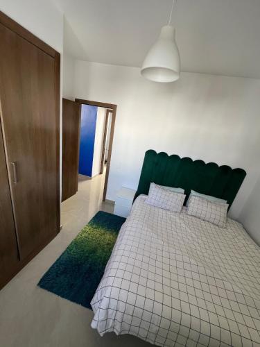 a bedroom with a bed with a green headboard at Joli et confortable appartement in Cabo Negro