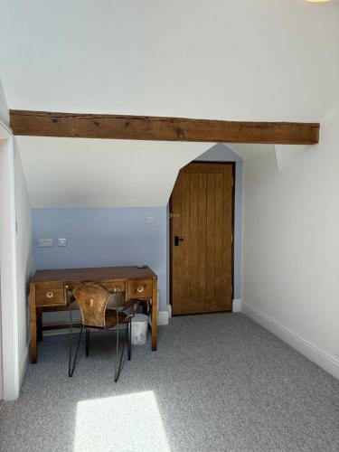 a room with a desk and a wooden door at Swallows Nest in Shrewsbury