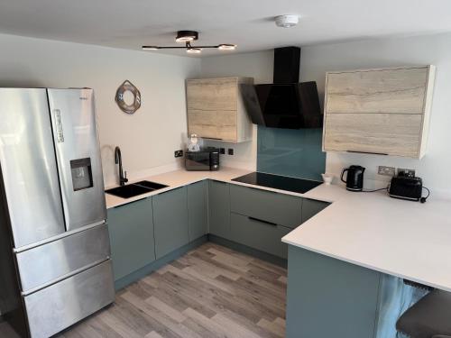 a kitchen with blue cabinets and a refrigerator at Lavish Filey Town Centre Apartment SKY 70inch TV Sleeps Up to 4 GREAT LOCATION in Filey