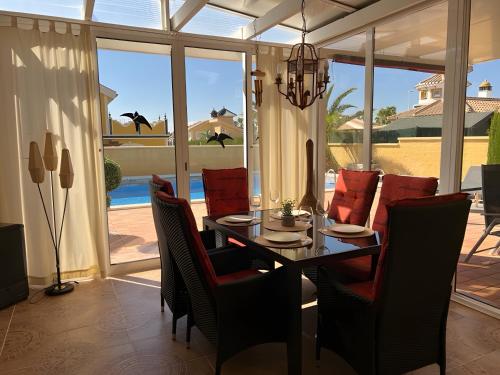 a dining room with a table and red chairs at Villa Casa del Sol in Mazarrón