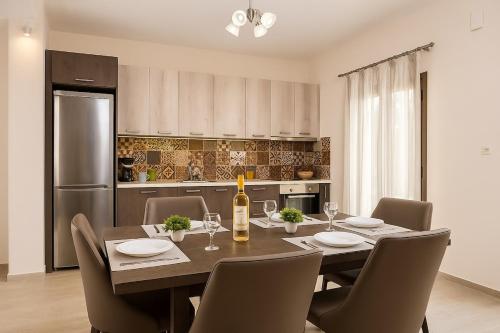 a dining room with a table with chairs and a bottle of wine at Harma Villa with Private Pool in Roúpai