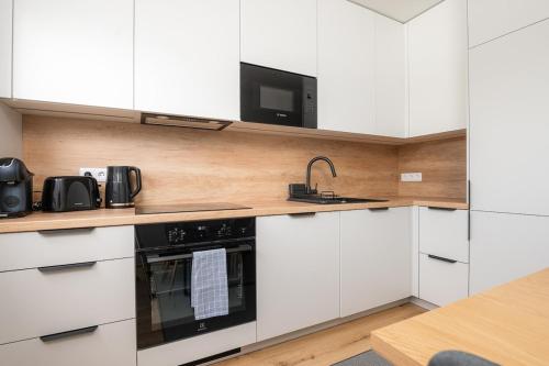 een keuken met witte kasten en een zwarte oven bij Mainiidu Apartment in Pärnu