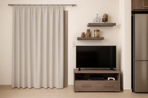 a living room with a television on a stand with a curtain at Harma Villa with Private Pool in Roúpai
