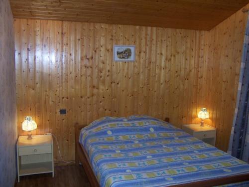 - une chambre avec des murs en bois et un lit avec deux lampes dans l'établissement Appartement 6 pers. avec jardin, proche pistes, animaux admis, Le Grand-Bornand Village - FR-1-467-80, au Grand-Bornand