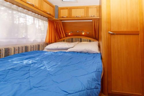 a bedroom with a blue bed in a room at Urlaub im Wohnwagen mitten im Wald in Lütow