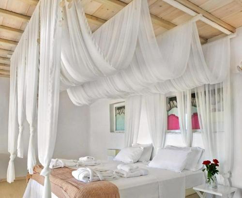 a bedroom with a canopy bed with white curtains at Luxury Mykonos Villa Kings And Queens Villa Private Pool Kastro in Mýkonos City