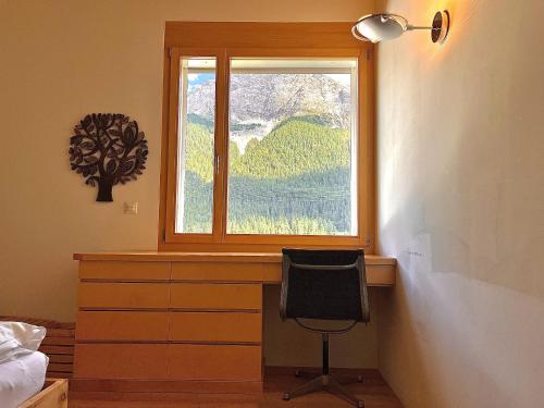 a bedroom with a window and a desk with a chair at Chesa Pino - Madulain in Madulain