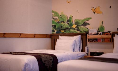 two beds in a room with a butterfly painting on the wall at Jeonju Wangyijimil Hanok Hotel in Jeonju
