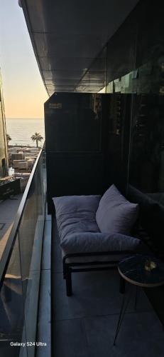 a bed on a balcony with the ocean in the background at Charming Batumi Apartment with City and Water Views in Batumi
