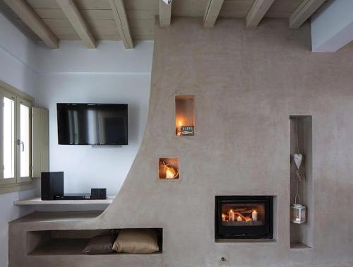 a living room with a fireplace and a tv at Elegant Astypalaia Villa Villa Bianca 2 Bedrooms Hot Tub & Beautiful Sea in Astypalaia Town