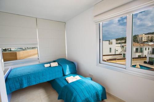 Habitación con 2 sillas azules y ventana en Apt Lasonos Asimi - Luxury 3 Bedroom Appartment - Protaras Apt With Communal Pool On Fig Tree Bay, en Protaras