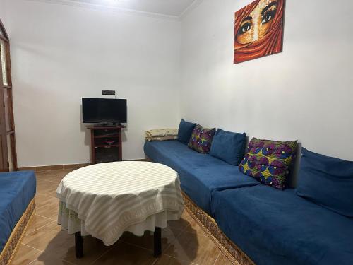 a living room with a blue couch and a table at Diki Beach Cosy place in Hammidane