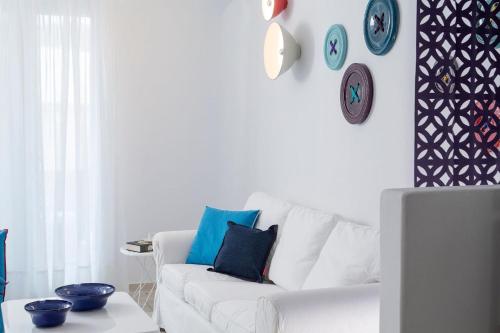a white living room with a white couch and clocks on the wall at Deluxe Mykonos Villa 2 Bedrooms Villa Del Sol Pool View Outdoor Pool Ornos in Mýkonos City