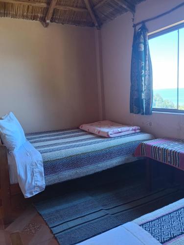 a small room with two beds and a window at Casa de Alejandra llachon in Llachon