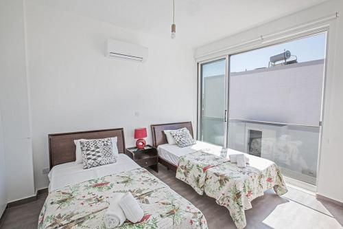 a bedroom with two beds and a large window at Villa Ochosto Eos - Luxury 5 Bedroom Protaras Villa With Private Pool - Close To The Beach in Protaras