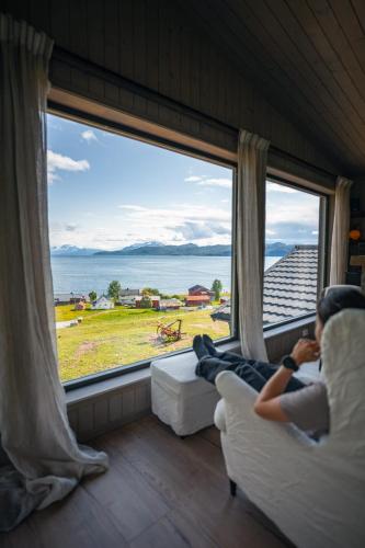 StraumsbuktaにあるYggdrasil Farmhotel Retreat, Spa & Yogaの大きな窓の前に座る者
