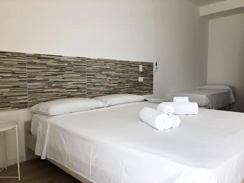 two beds in a bedroom with white sheets and towels at Accòmodati - Camere e Appartamenti in Marina di Gioiosa Ionica