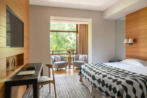 a hotel room with a bed and a desk and a balcony at Hôtel Ermitage in Évian-les-Bains