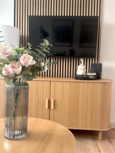a vase of flowers sitting on a table with a television at Almondvale Apartment in Livingston