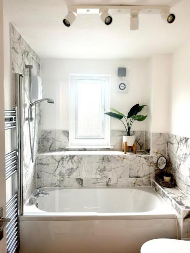 a white bath tub in a bathroom with a window at Almondvale Apartment in Livingston