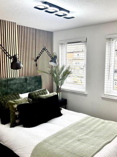 a bedroom with a large bed and two windows at Almondvale Apartment in Livingston