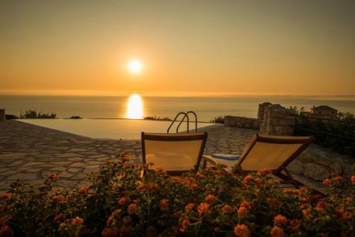 two chairs sitting on a patio with the sunset in the background at Extravagant Zante Villa Villa Crystal Great Sea Views 3 Bedrooms Agios Nikolaos in Koríthion