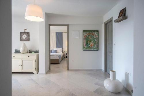 una stanza bianca con un letto e un vaso sul pavimento di Platinum Paros Villa Ocyrhoe Iii Villa 4 Bedrooms Private Pool & Fantastic Sea Views Parikia a Paroikia